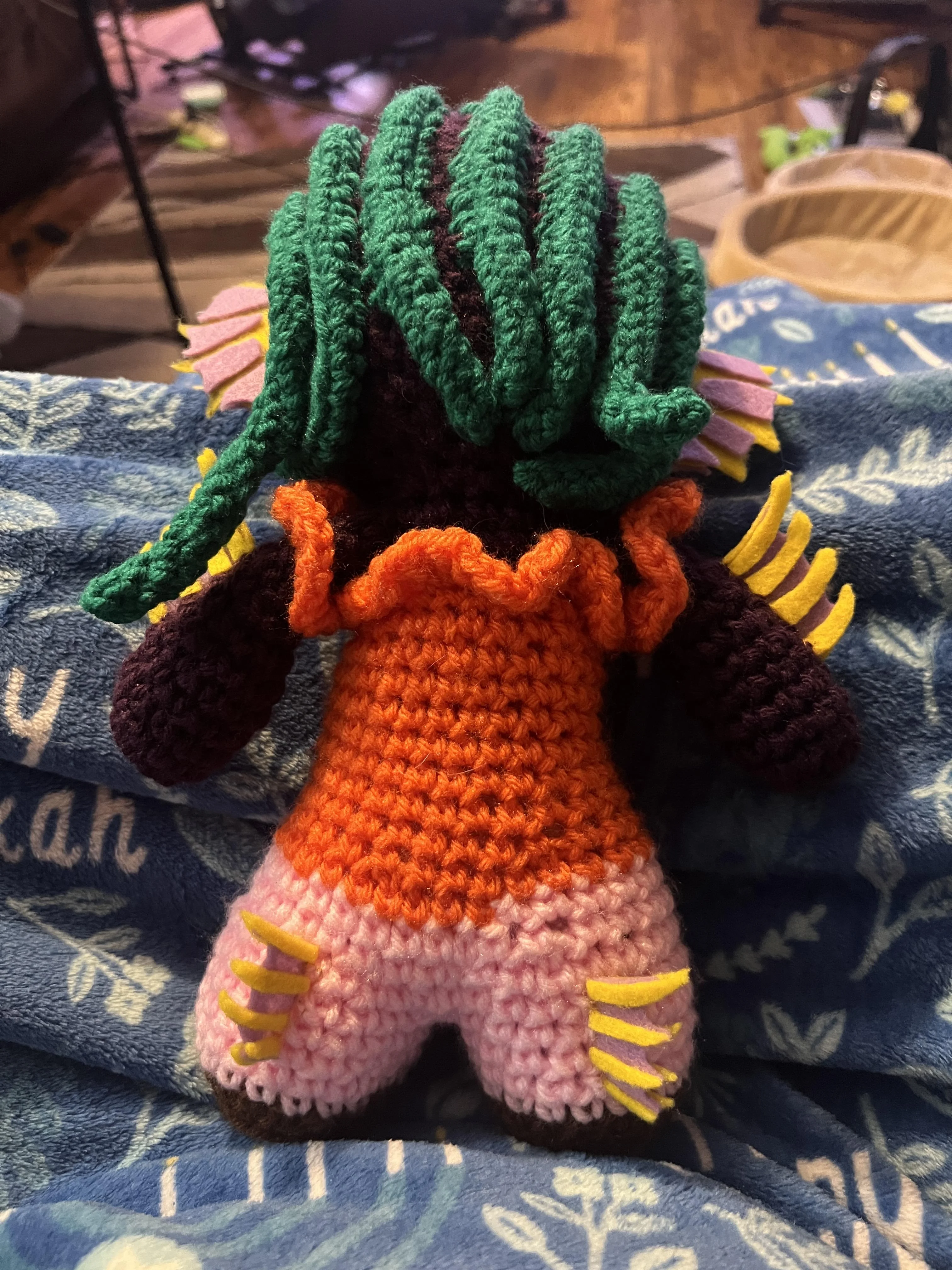 Back of crochet doll showing green braids and felt fins on the back of the legs